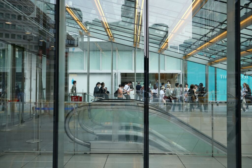 A bustling scene at Yokohama station with a crowd navigating modern escalators indoors.