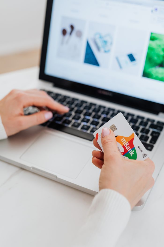 Person using a credit card for online shopping on a laptop, showcasing e-commerce concept.